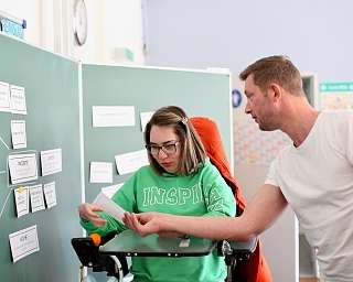 Eine Person unterstützt eine andere beim Lernen in einem Klassenzimmer.