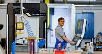 Ein Mitarbeiter bedient eine CNC-Maschine in einer Werkstatt.