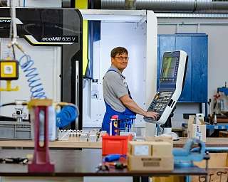Ein Mitarbeiter bedient eine CNC-Maschine in einer Werkstatt.