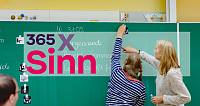 Lehrer und Schüler interagieren an einer Tafel im Klassenzimmer.